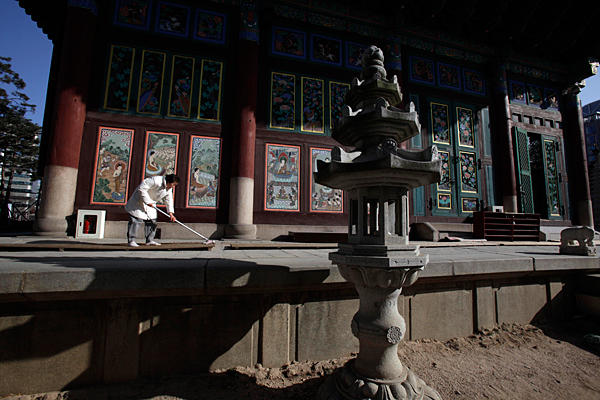 A South Korean woman cleans the walkway outside a Buddhist temple in Seoul